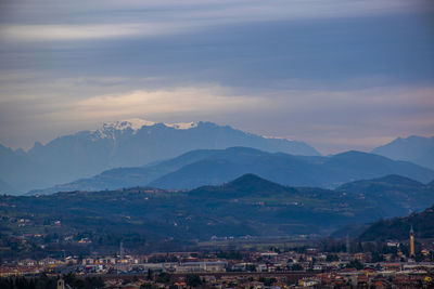 Aerial view of townscape and mountains against sky