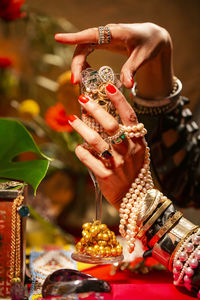 Cropped hands of woman holding champagne flute with jewelry