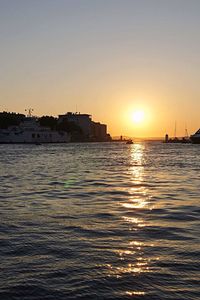 Buildings by sea against clear sky during sunset