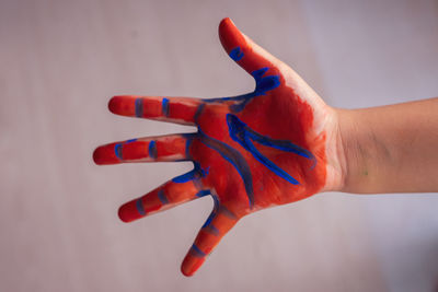 Red and blue, multi coloured child's painted hand up on the white background