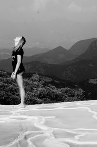 Side view full length of woman standing against mountains