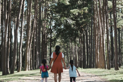 Rear view of mother and kids walking in forest