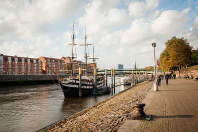 Boats moored at harbor against sky in city