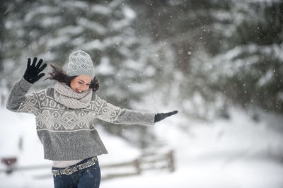 Happy woman wearing knitwear dancing in the snow