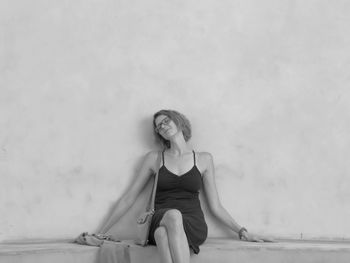 Fashion model sitting against wall