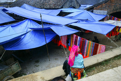 Rear view of person sitting by tarpaulins