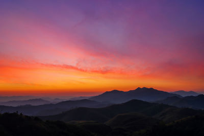 Scenic view of silhouette mountains against romantic sky at sunset