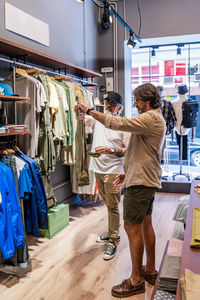 Side view clothing store owner helping new customer to choose a shirt