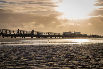 Silhouette pier over sea against sky during sunset