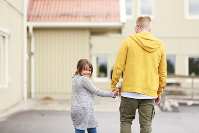 Rear view of father with son standing outdoors