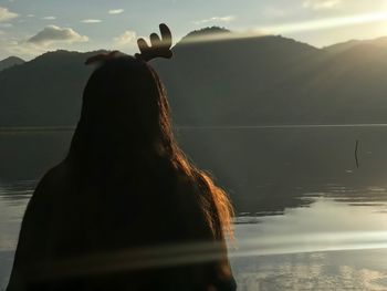 Rear view of woman looking at lake against mountain range