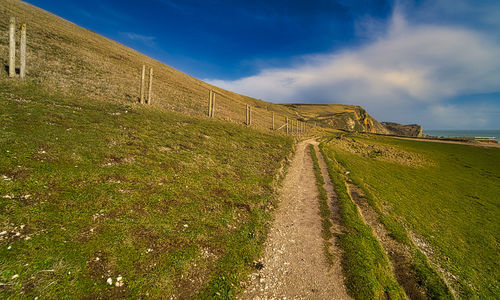 Road amidst field against sky