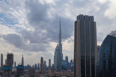 Skyscrapers in city against cloudy sky