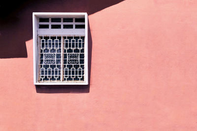 Low angle view of window on pink wall of abuilding