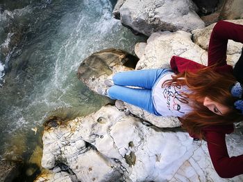 Woman sitting on rock over sea