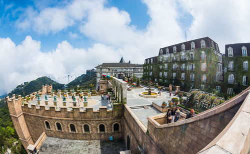 Fish-eye lens shot of buildings in city against cloudy sky