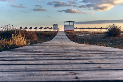 Boardwalk leading towards sea against sky