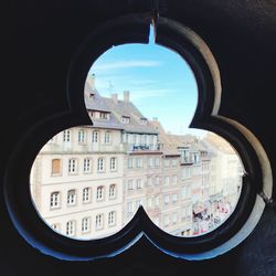 Buildings against sky seen through glass window