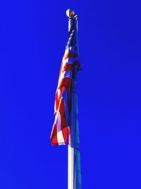 Low angle view of flag against clear blue sky