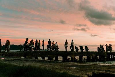 People pier over sea against sky during sunset