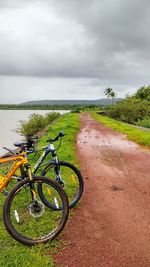 Bicycle by road on field against sky