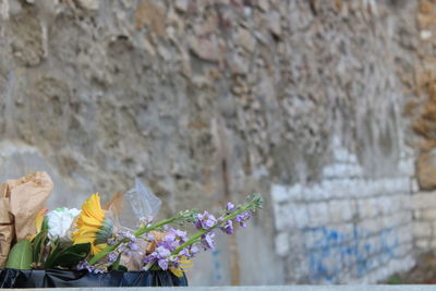 Flowers with garbage in recycling bin against wall