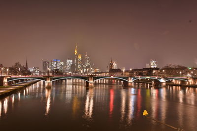 Illuminated bridge over river at night