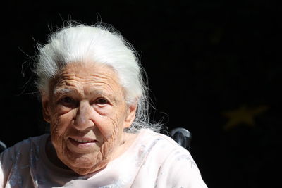 Portrait of smiling senior woman against black background