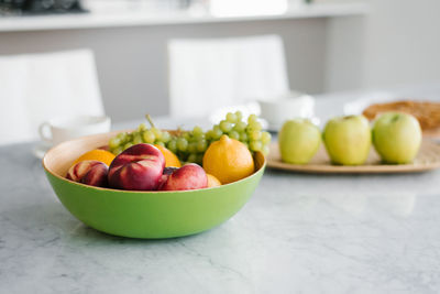 Plate with different fruits on kitchen table