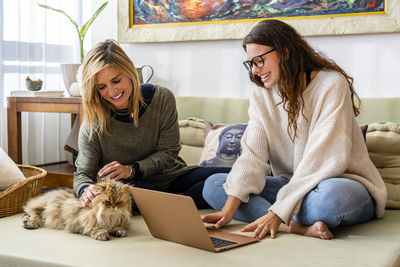 Woman using phone while sitting on laptop