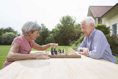 Senior couple playing chess in garden