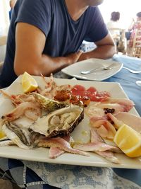 Midsection of man having various seafood on table at restaurant