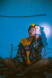 Young woman sitting on bed in darkroom