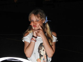 Smiling girl standing against illuminated camera at night