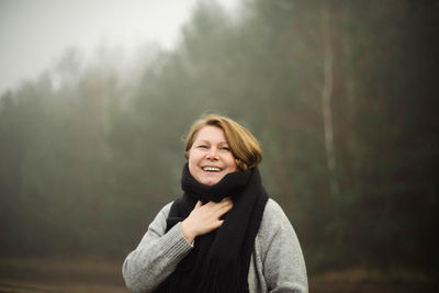 Woman standing by forest in foggy weather