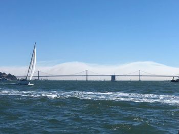 View of suspension bridge over sea against clear blue sky