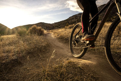 Young woman mountain biking during sunset in mountains