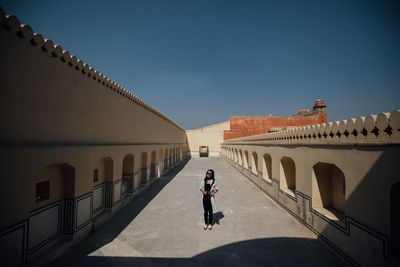Woman walking on historic building against sky