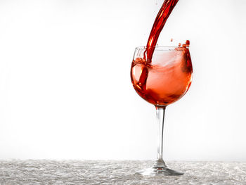 Close-up of wineglass on glass against white background