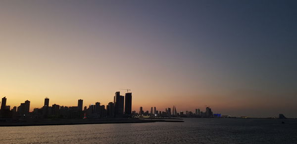 Sea and buildings against sky during sunset