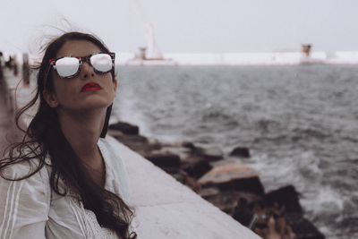 Portrait of woman wearing sunglasses against sea