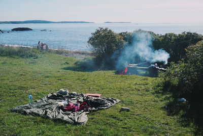 Picnic blanket at grassy beach against people