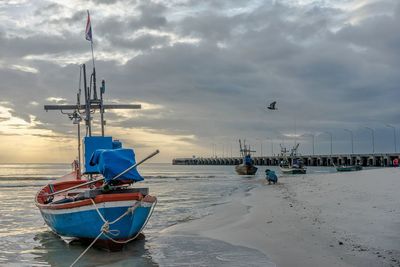 Sailboat moored on beach against sky