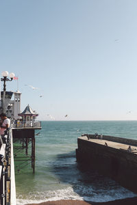 Birds flying over sea against clear sky seen from brighton palace pier