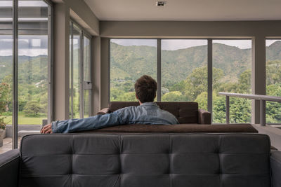 Rear view of man sitting on sofa