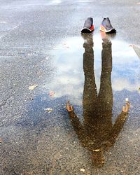 Reflection of man in puddle on road