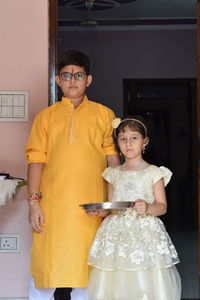 Portrait of siblings standing at home