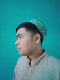 Portrait of young man looking away against blue background