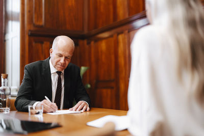 Senior businessman signing contract document with financial advisor in board room meeting