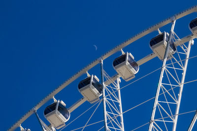 Low angle view of ferris wheel against clear blue sky